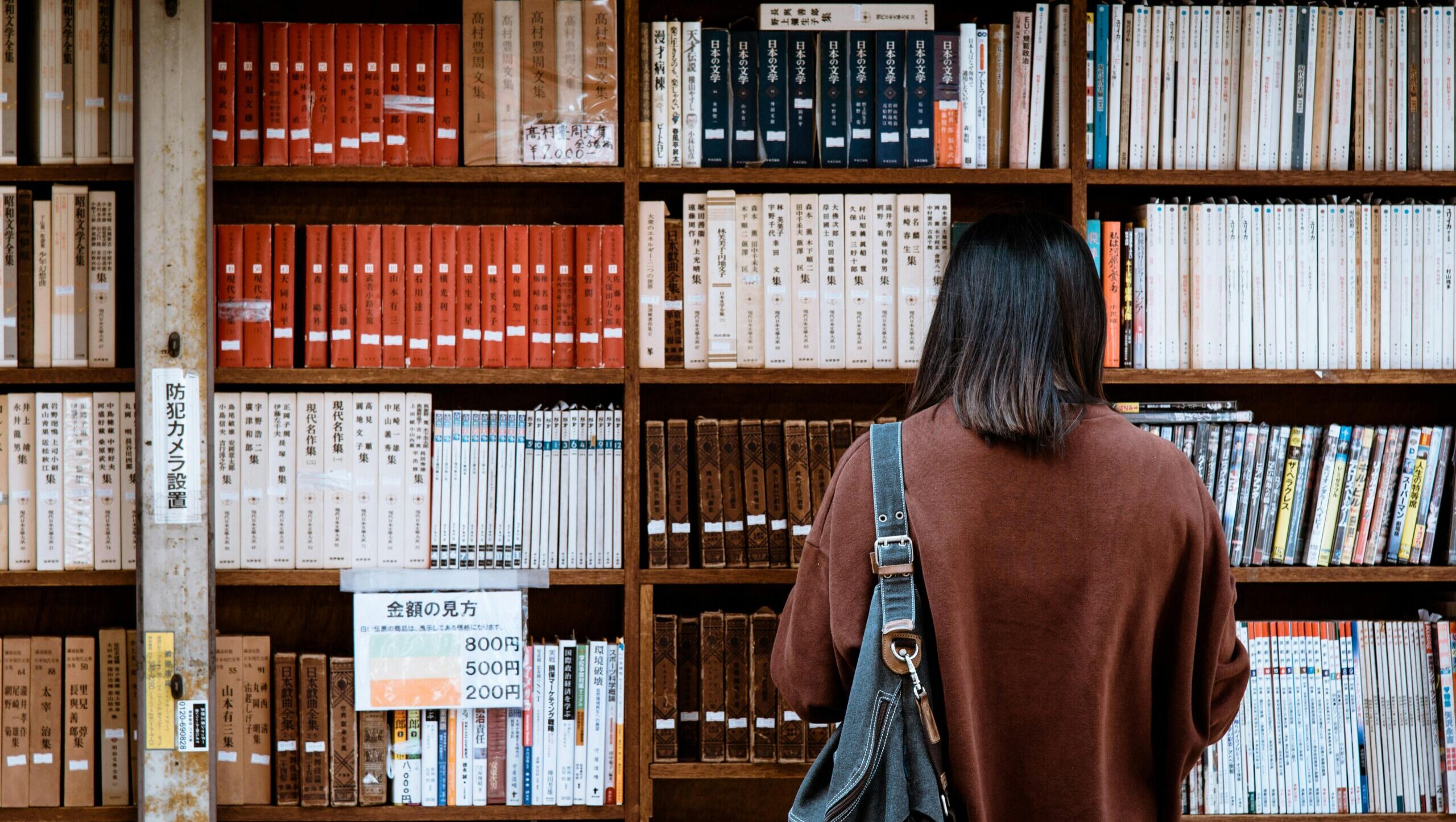 Woman browsing books at a library in Nagano, Japan. Explore knowledge and literature.