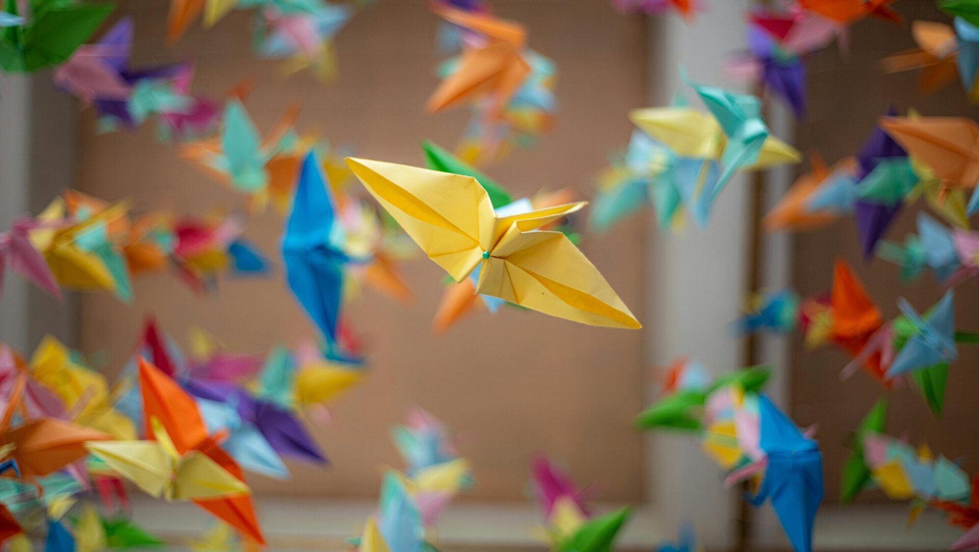 Vibrant origami cranes float in a serene Japanese garden setting, capturing a cultural essence.