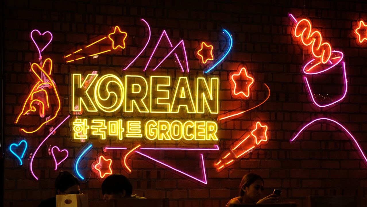 Colorful neon sign with Korean text in a dimly lit shop, highlighting a vibrant urban culture.